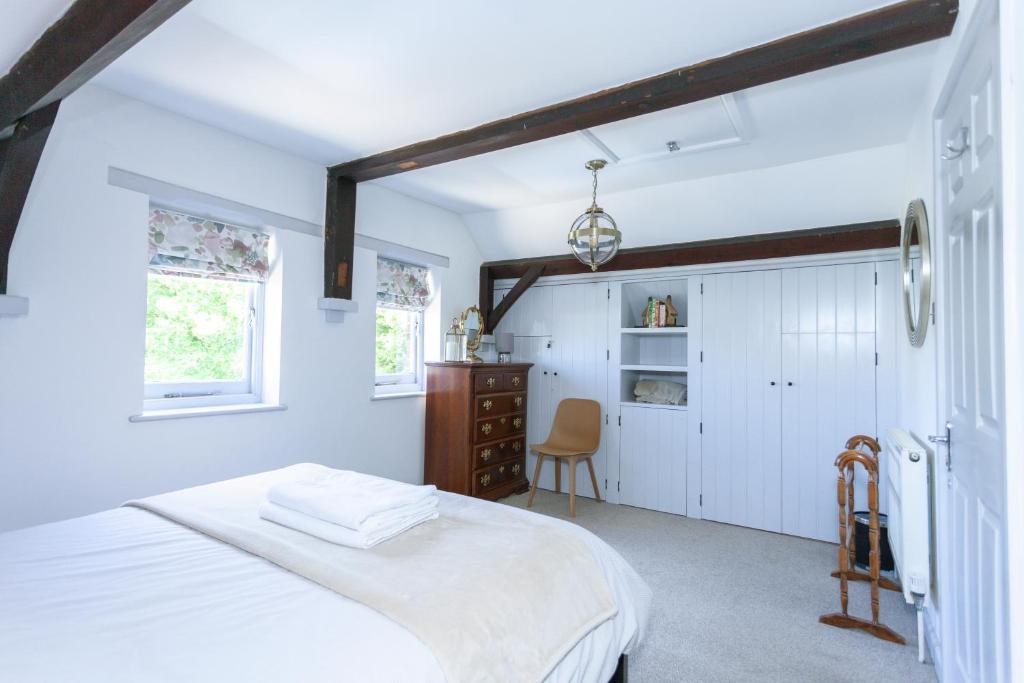 a white bedroom with a bed and a chair at The Old Schoolhouse in Whitstable