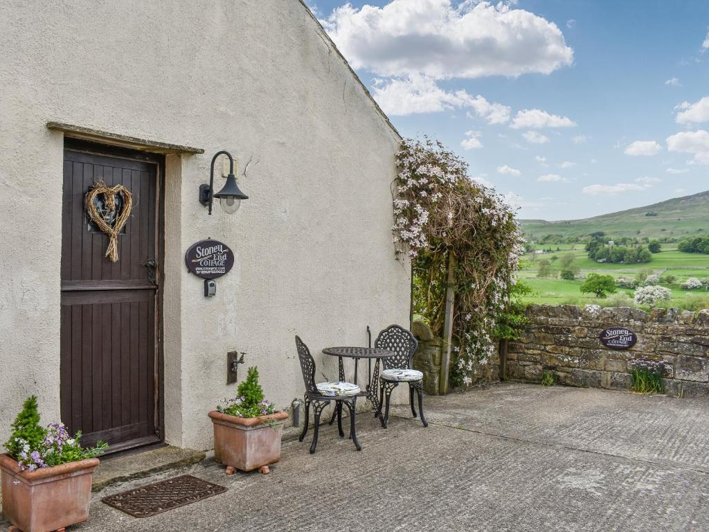 a patio with a table and chairs outside of a building at Stoney End Cottage in Askrigg