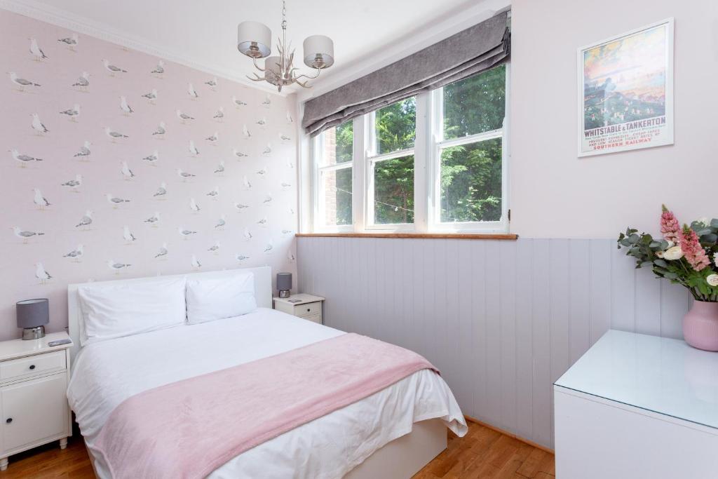 a white bedroom with a bed and a window at The Old Schoolhouse in Whitstable