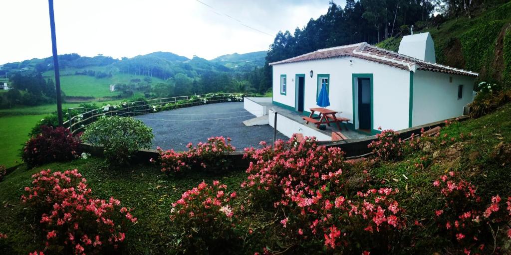una pequeña casa blanca en una colina con flores en Casa dos Valentes en Santo Espírito