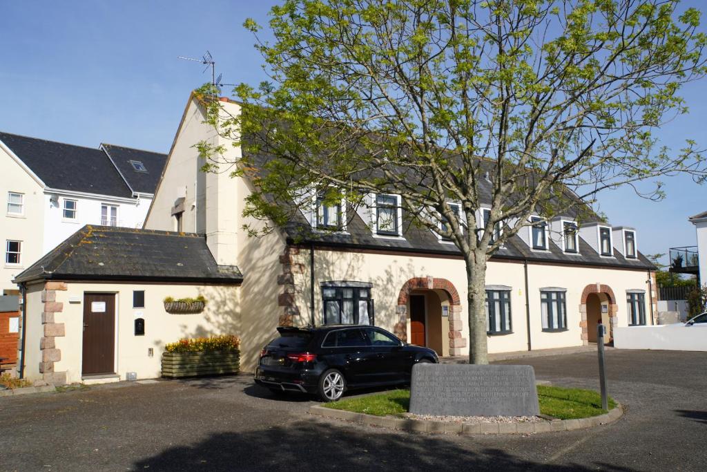 ein schwarzes Auto, das vor einem weißen Gebäude geparkt ist in der Unterkunft The Uplands Apartments in Saint Helier Jersey