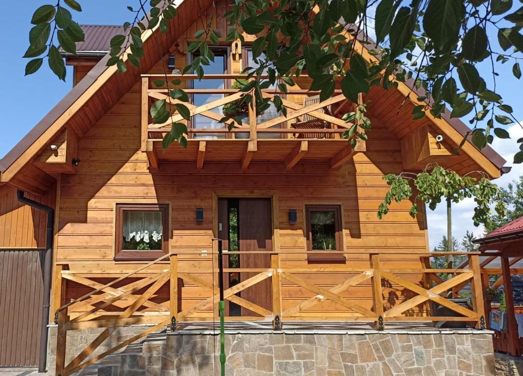 uma cabana de madeira com um alpendre e um portão em Domek na Polance em Istebna