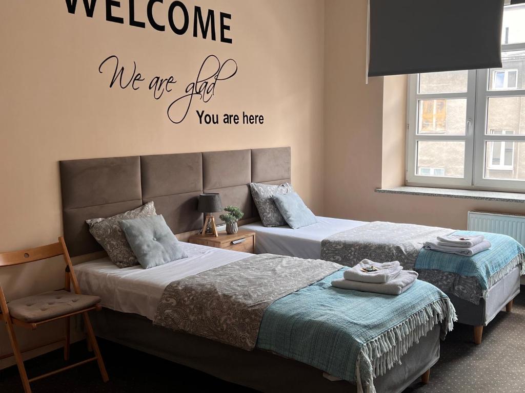 a bedroom with two beds and a welcome sign on the wall at Apartamenty Azzurro in Kielce