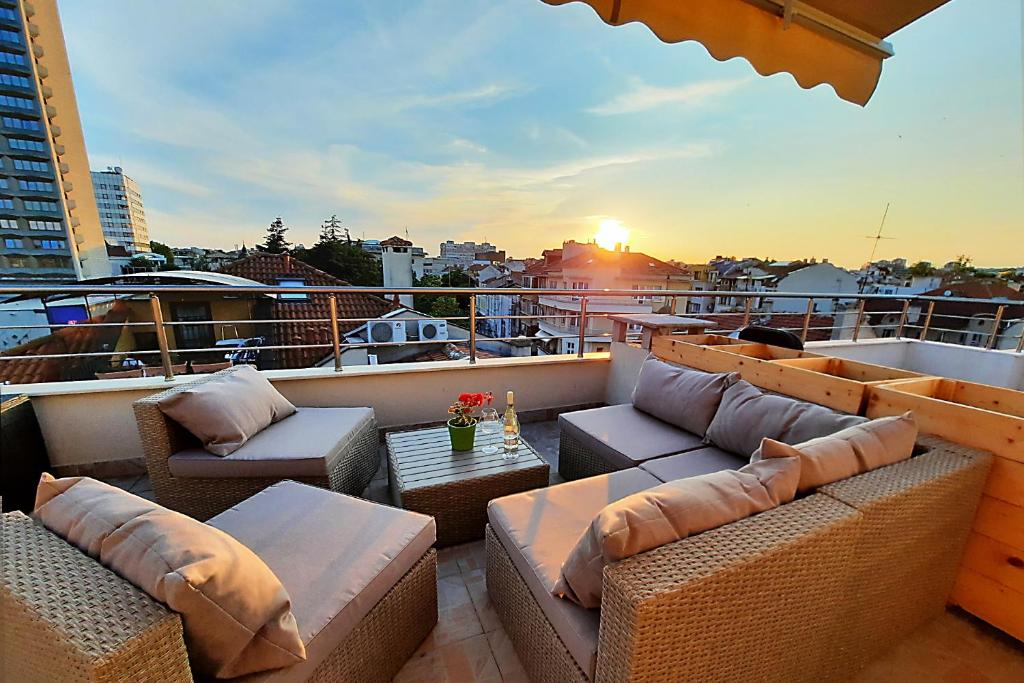 eine Terrasse mit Sofas und Tischen auf dem Balkon in der Unterkunft Shik & Chic in the Heart of Burgas # 5min from beach # New in Burgas City
