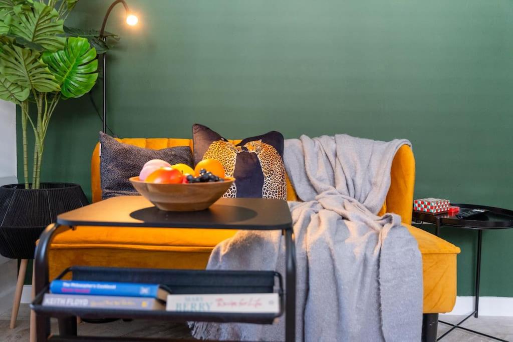 a yellow couch with a bowl of fruit on a table at Stylish Cardiff City Apartment with Parking in Cardiff