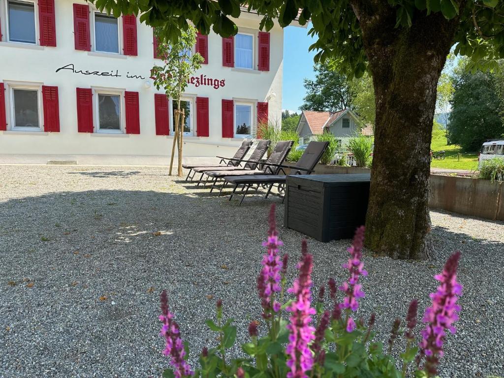 a group of benches in front of a building with pink flowers at Gasthof - Auszeit im Bad Diezlings - Adults only in Hörbranz
