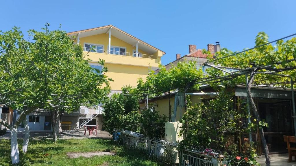 a yellow house with trees in front of it at стаи за гости Росица in Ravda