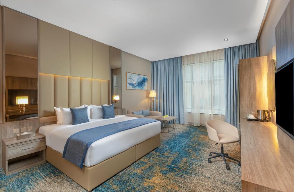 um quarto de hotel com uma cama grande e uma secretária em Seven Gardens Hotel em Riade