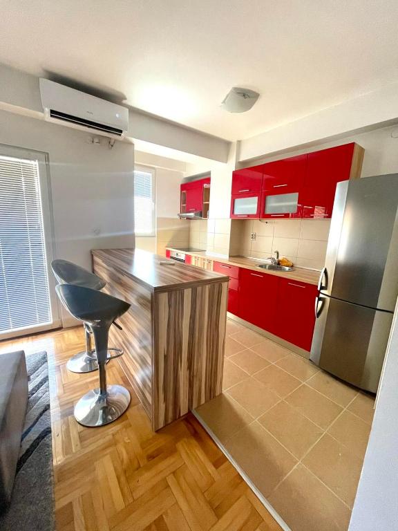 una cucina con mobili rossi e un frigorifero in acciaio inossidabile di Apartman Aleksa a Skopje
