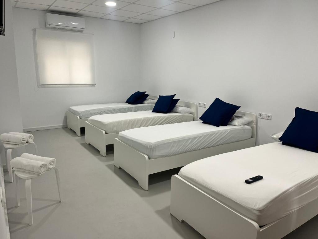 a room with four beds with blue pillows at Hotel Hospedarte, SL in Riba-Roja De Turia
