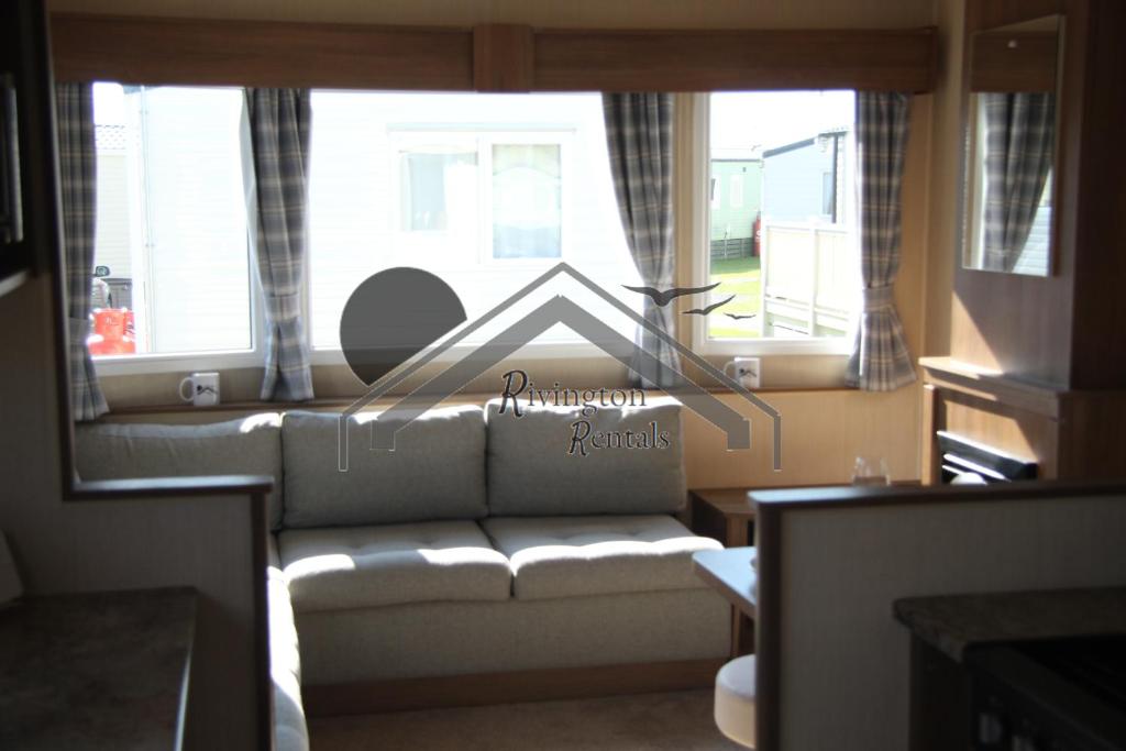 a living room with a couch in front of a window at The Rivington Lodge in Heysham
