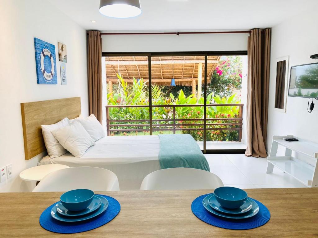 Cette chambre comprend un lit et une table avec des plats bleus. dans l'établissement Mar Turquesa Eco Pousada, à Maragogi
