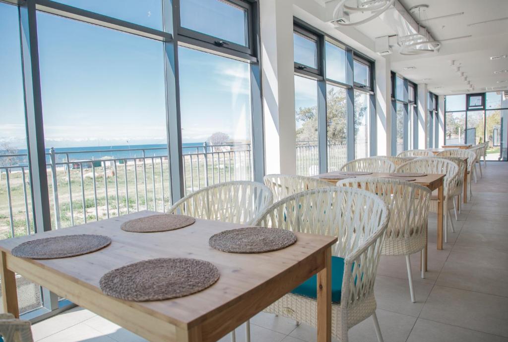 una fila de mesas y sillas en una habitación con ventanas en Silence hotel en Cholpon-Ata