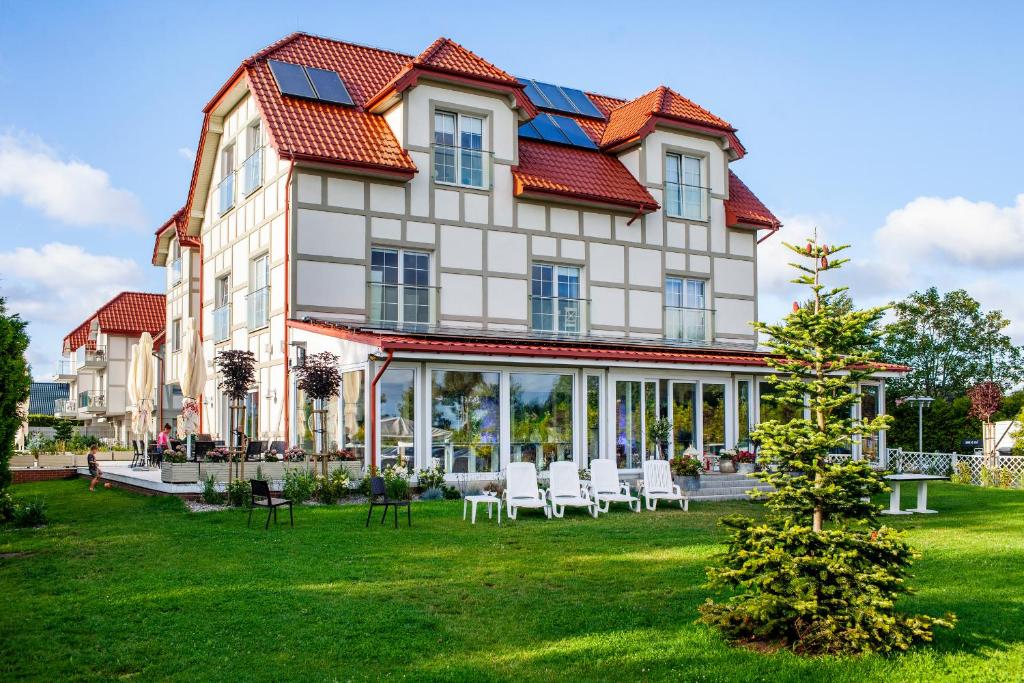 een groot gebouw met witte stoelen op een gazon bij Dębki Playa Apartments in Dębki