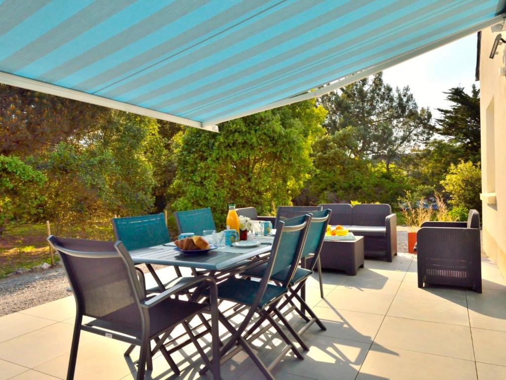 patio con tavolo e sedie sotto un tetto blu di Holiday Home Melflo by Interhome a Piriac-sur-Mer