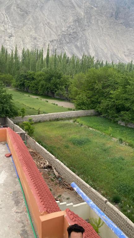 a person sitting on a bench overlooking a field at Kamals Lodge in Skardu