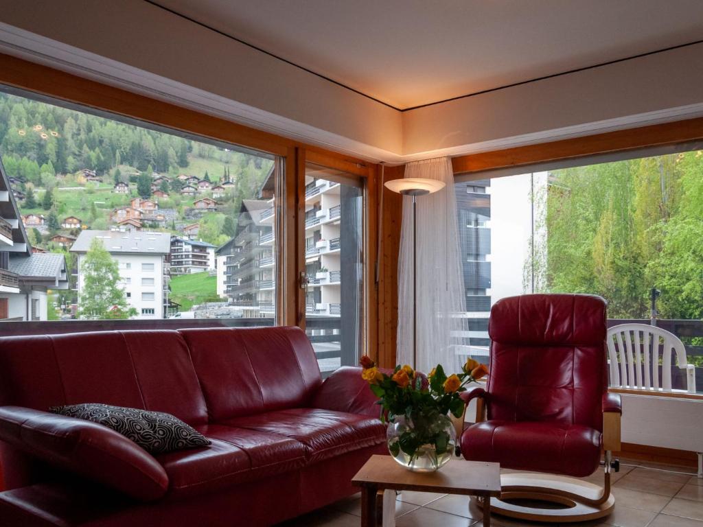 sala de estar con sofá, silla y ventanas grandes en Apartment Diana E2 by Interhome, en Nendaz