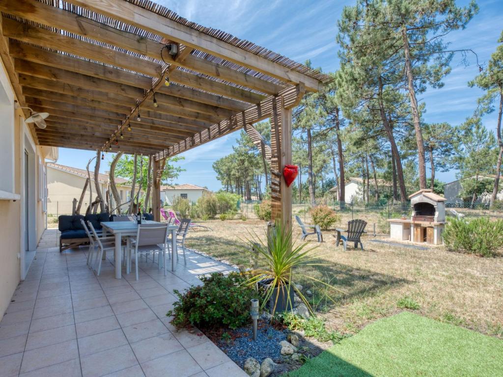 eine Terrasse mit einer Holzpergola sowie einem Tisch und Stühlen in der Unterkunft Holiday Home Les Ormes by Interhome in Montalivet-les-Bains