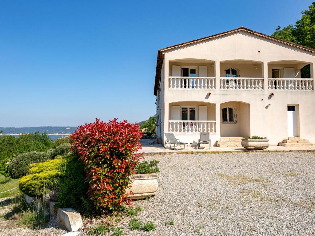 a large white house with a balcony and red flowers at Apartment Aiguines by Interhome in Bauduen