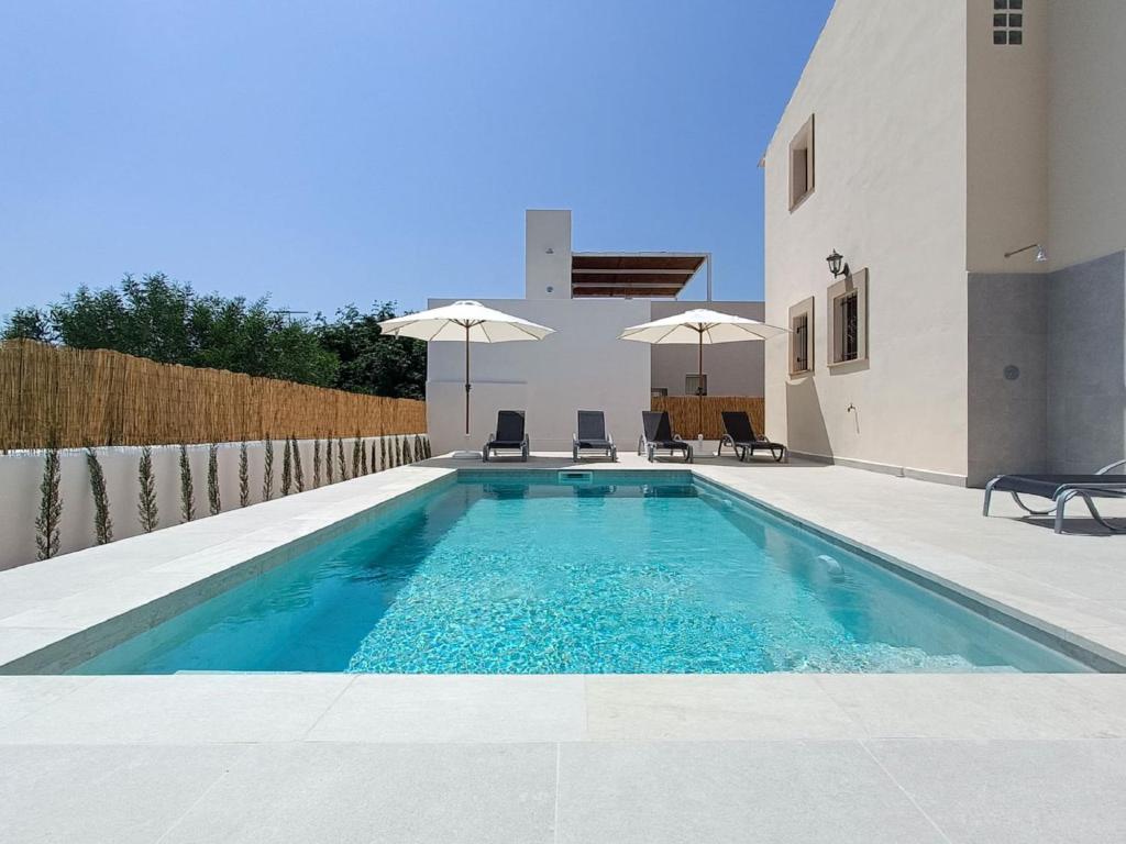 una piscina con sillas y sombrillas junto a una casa en Villa Es Trenc Pool-Beach House by Interhome, en Sa Ràpita