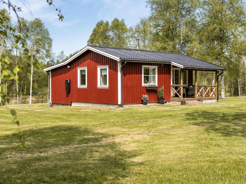 uma cabina vermelha com um grande campo de relva em Chalet Björkebo - HAL024 by Interhome em Ätran