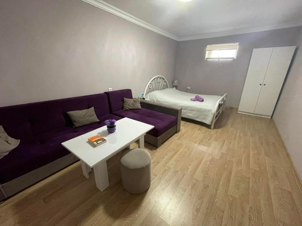 uma sala de estar com um sofá roxo e uma cama em Ekas apartamenti em Tbilisi