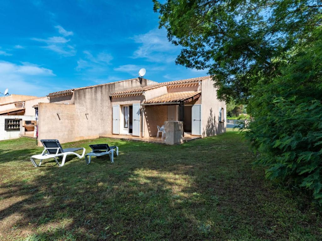 a yard with two chairs and a building at Holiday Home La Pinede - SAG171 by Interhome in Sagone