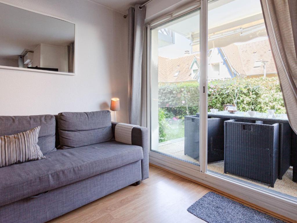 a living room with a couch and a large window at Apartment Hortensia by Interhome in Cabourg