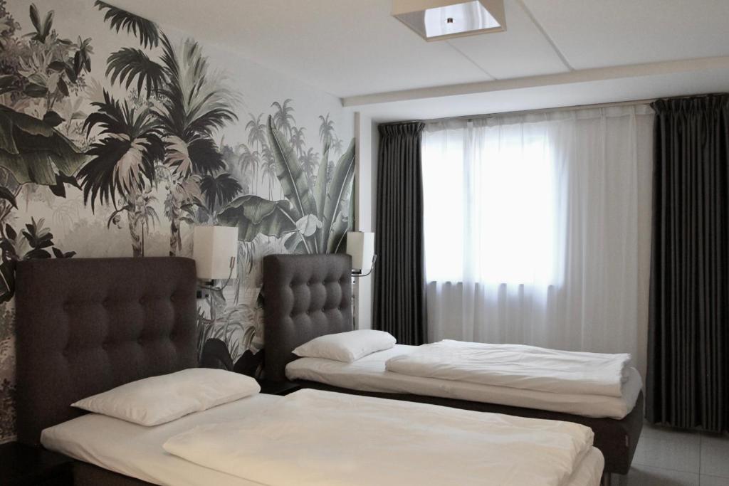 Super Stay Hotel, Oslo في أوسلو: غرفة نوم بسريرين وورق جدران استوائي