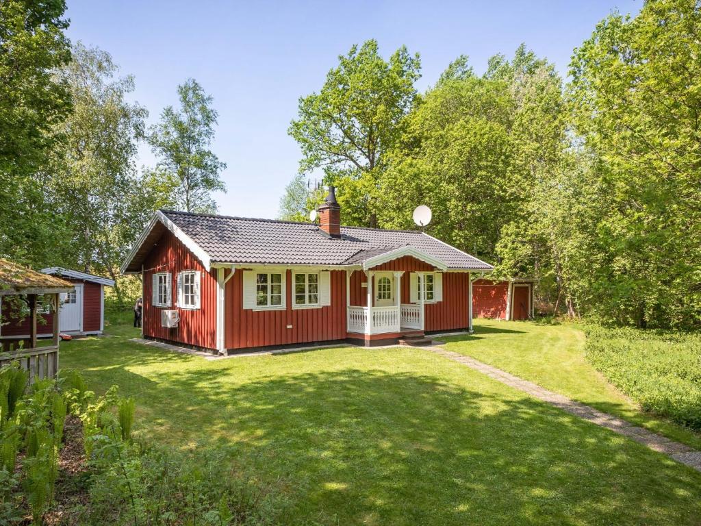 uma casa vermelha num quintal com relva em Chalet Skogsgläntan - HAL023 by Interhome em Ätran