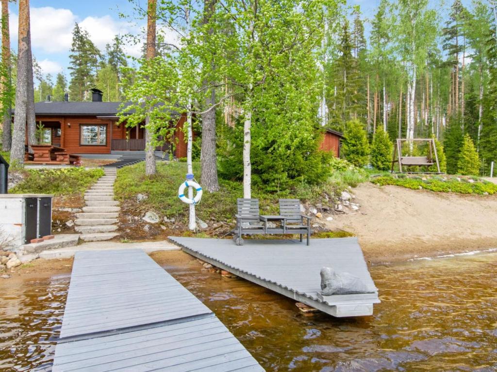 a house with two chairs on a dock in the water at Holiday Home 7152 by Interhome in Kaartilankoski