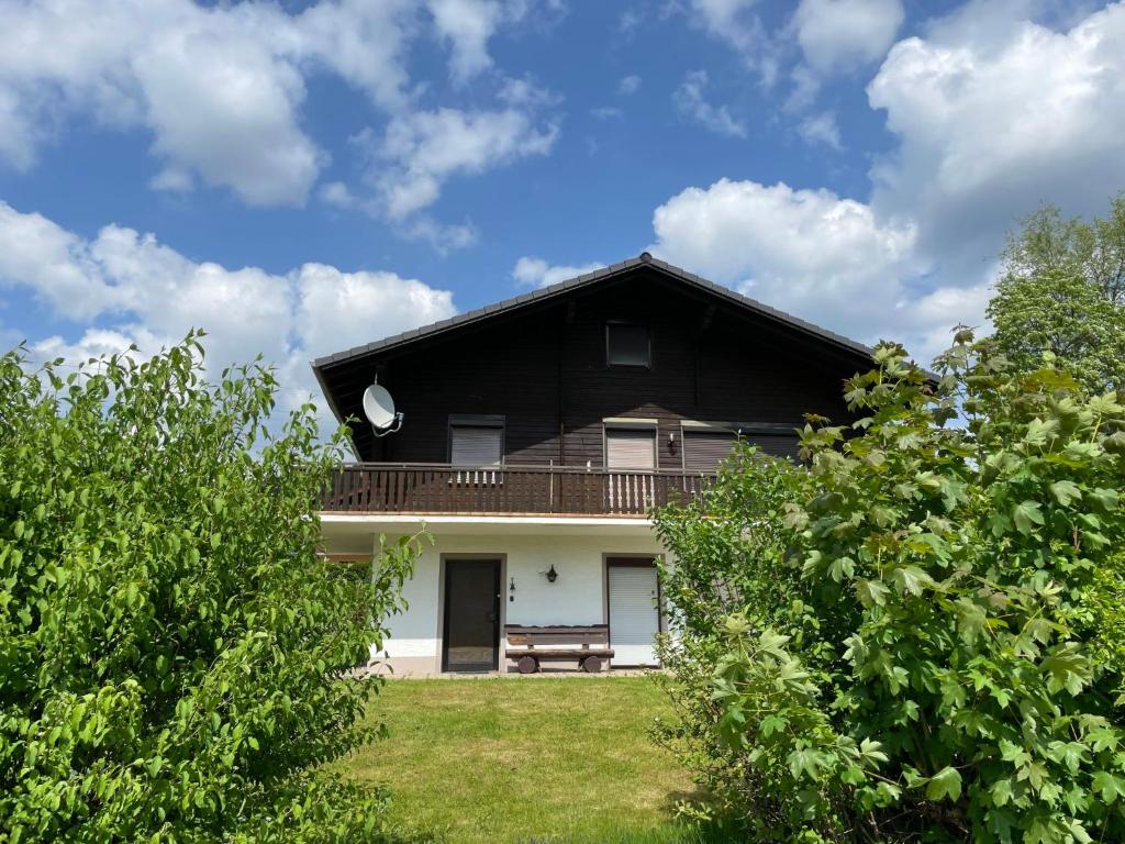 ein schwarzweißes Haus mit einer Bank im Hof in der Unterkunft Apartment Am Hohen Bogen-11 by Interhome in Arrach