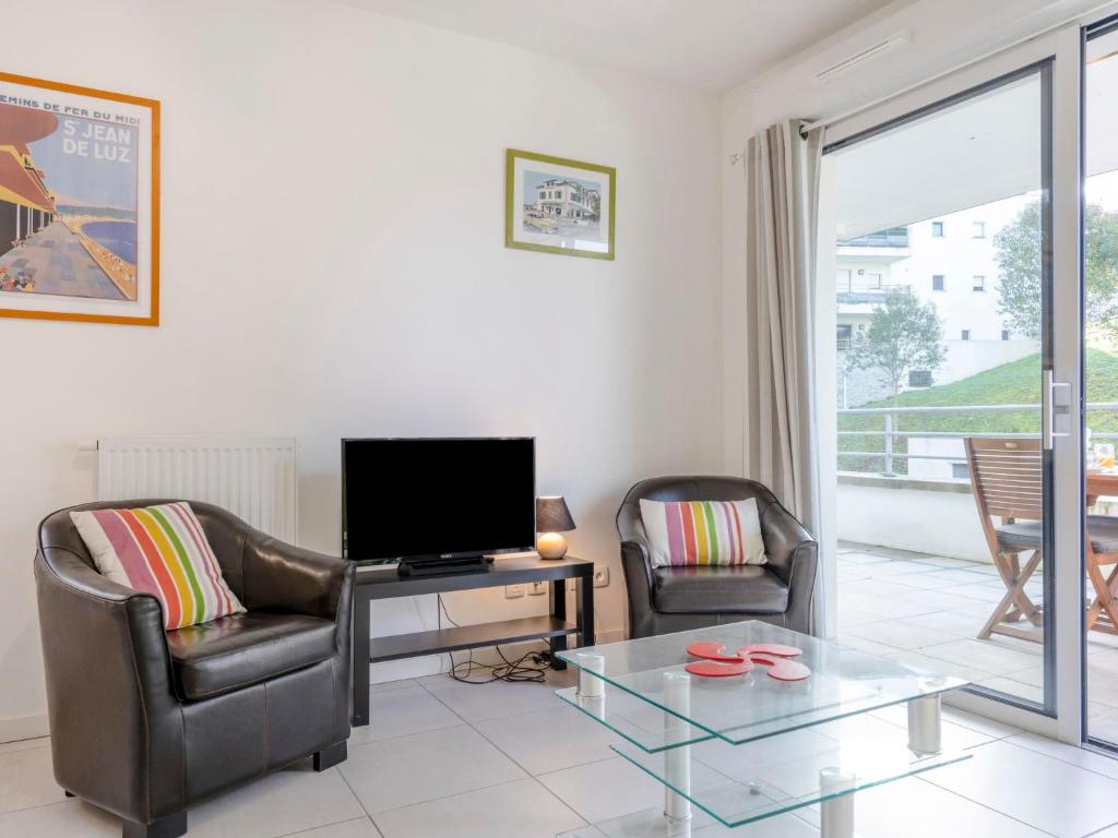 ein Wohnzimmer mit einem TV, 2 Stühlen und einem Tisch in der Unterkunft Apartment Résidence Hego Alde by Interhome in Saint-Jean-de-Luz