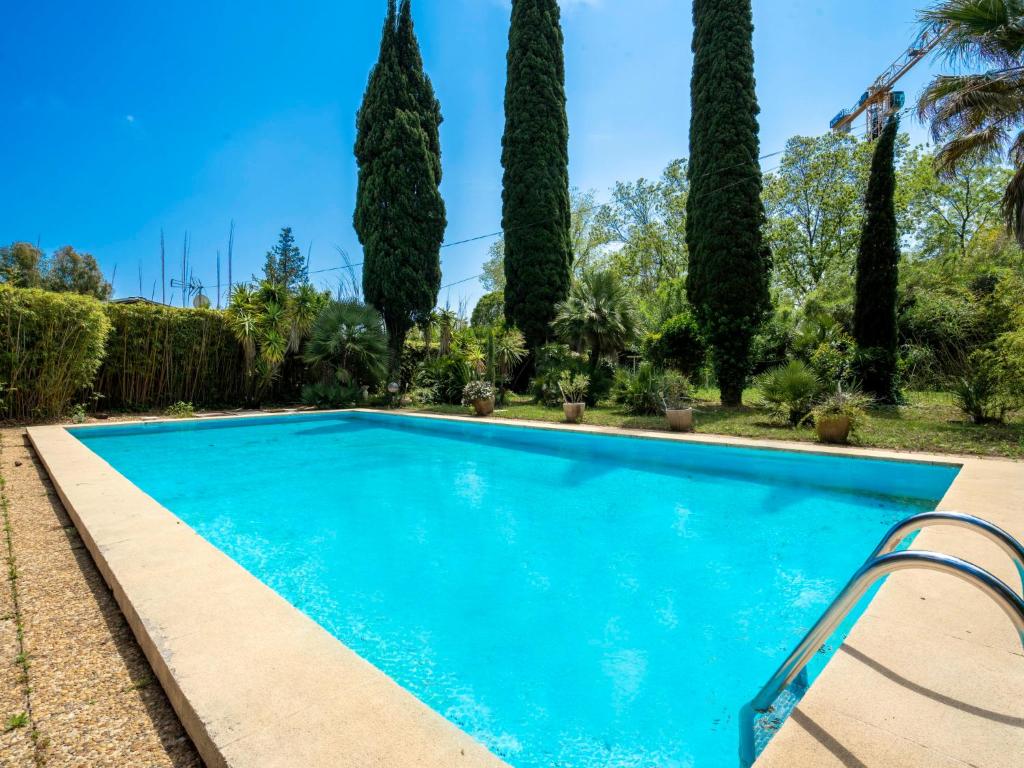 une piscine bleue avec des arbres en arrière-plan dans l'établissement Apartment Le Bouisset by Interhome, à Saint-Aygulf