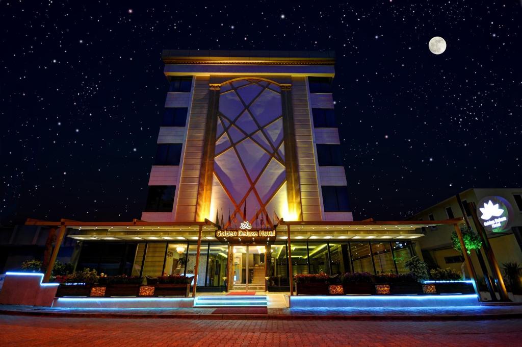 un edificio con una torre de reloj por la noche en Golden Deluxe Hotel, en Adana