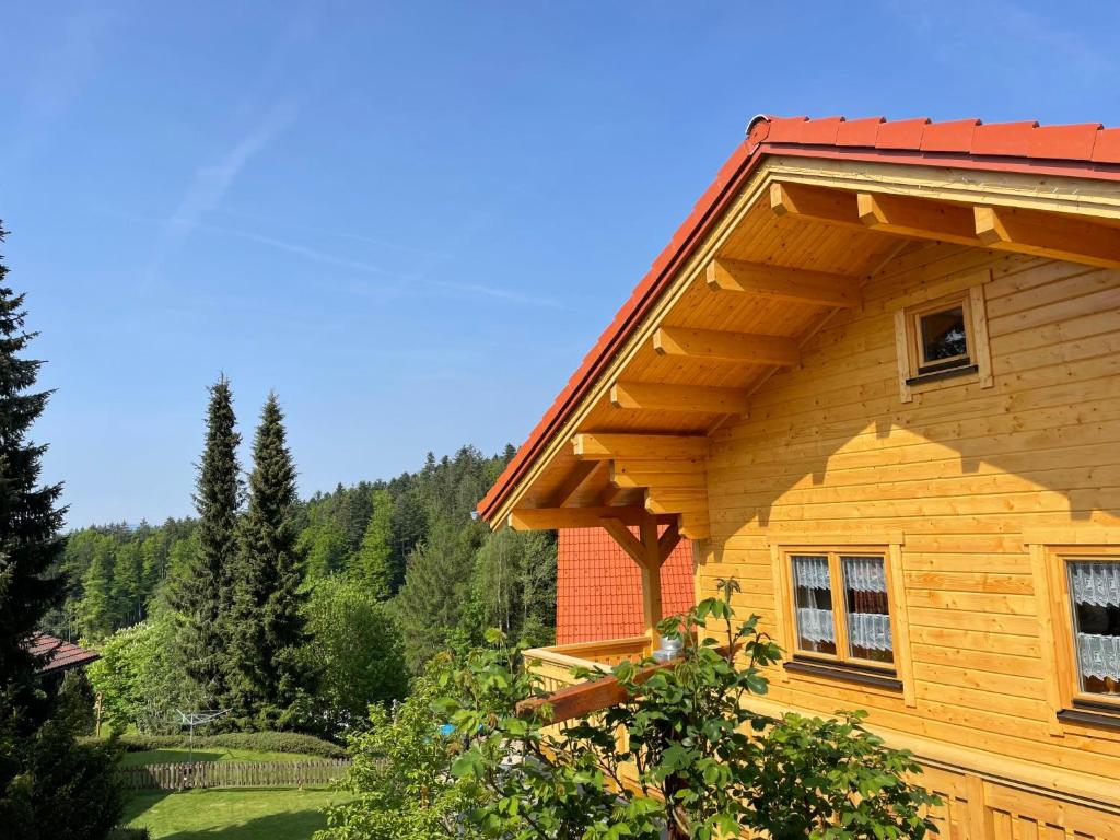 une maison en bois avec un toit rouge et des arbres dans l'établissement Holiday Home Chalet Toni mit Sauna by Interhome, à Spiegelau