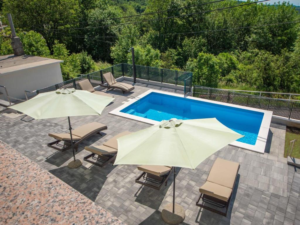 a swimming pool with two umbrellas and chairs next to it at Holiday Home Nola by Interhome in Viskovo