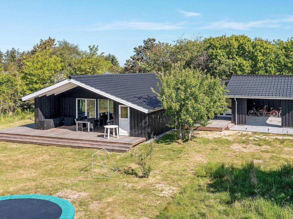 ein schwarzes Haus mit einer Terrasse und einem Hof in der Unterkunft Holiday home Bindslev XXIII in Bindslev