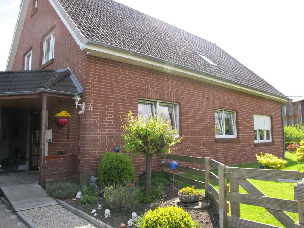 a red brick house with a fence in front of it at Apartment Strandkorb by Interhome in Hooksiel