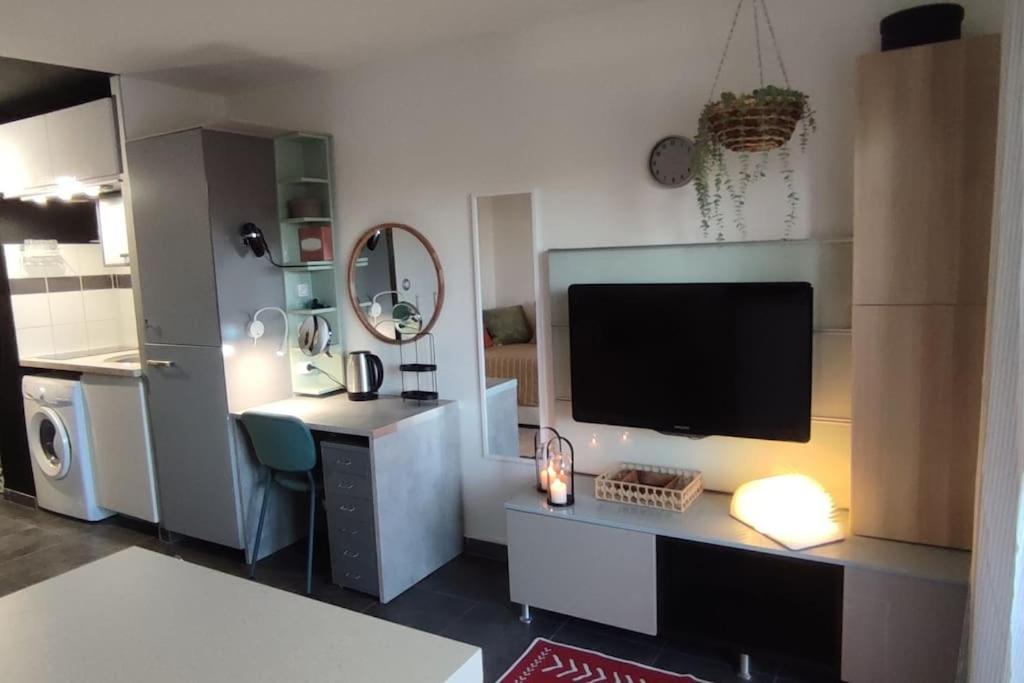 - un salon avec une télévision et un bureau avec une télévision dans l'établissement CADUCÉE Studio climatisé balcon ensoleillé parking proche Montpellier, à Grabels
