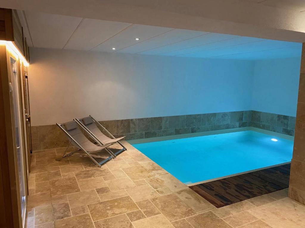 einen Pool mit einem Sessel und einem blauen Licht in der Unterkunft Lush holiday home in Theux with heated indoor pool in Sprimont