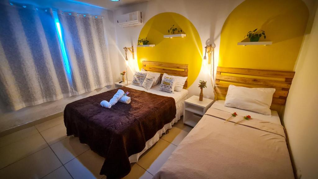 a bedroom with two beds and a mirror at Cantinho da Gê Suítes in Porto De Galinhas