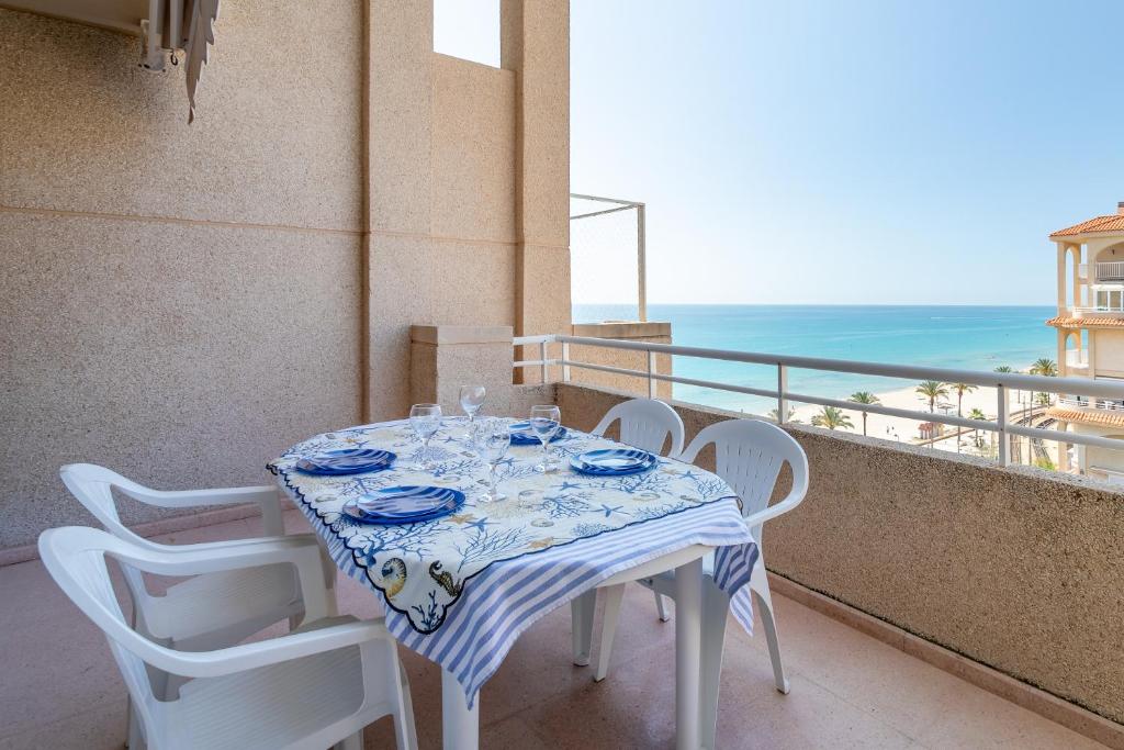 een tafel en stoelen op een balkon met uitzicht op de oceaan bij Duplex Sorolla in La Venteta