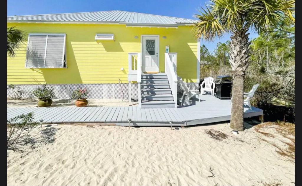 ein gelbes Haus mit einer Terrasse und einer Palme in der Unterkunft Sunnydaze Beach Pools Ask For Special May in Gulf Shores