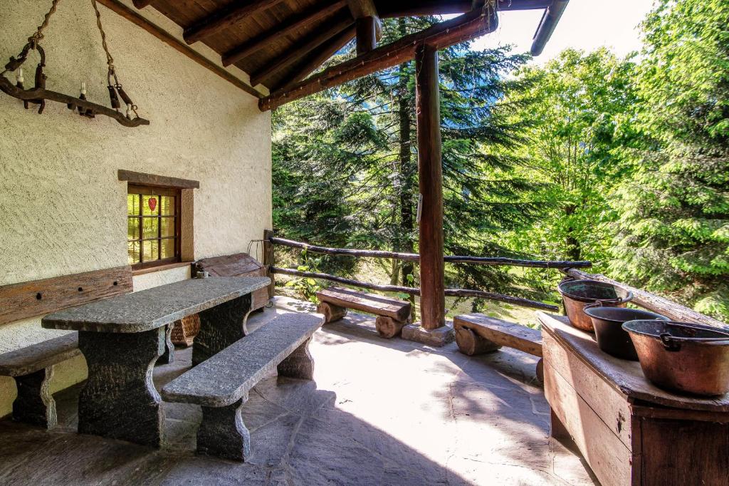 a patio with benches and potted plants on a porch at Casa al Fiume by Quokka 360 - House by the River in the Verzasca Valley in Lavertezzo