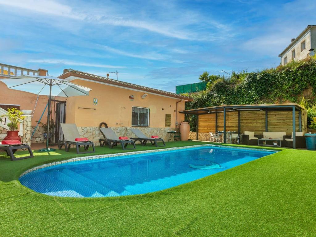 un patio trasero con piscina y césped verde en Holiday Home Aguilera by Interhome, en Maçanet de la Selva