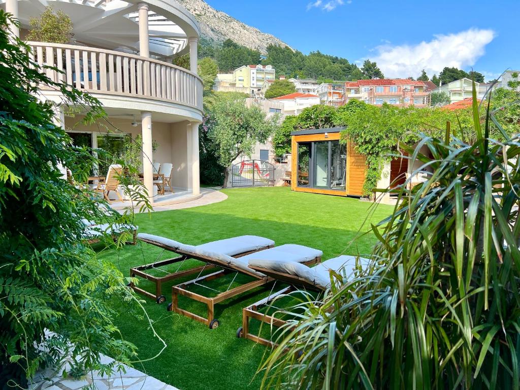a backyard with a lawn with chairs and a house at Villa Romana III Omis in Omiš
