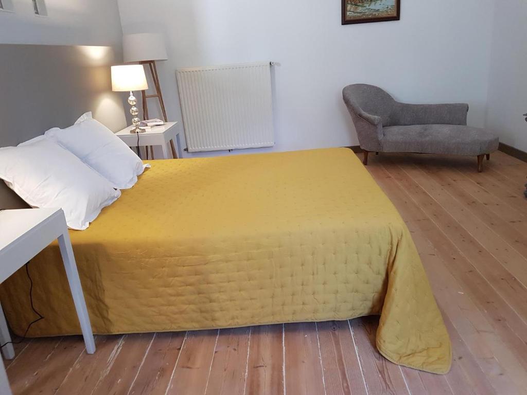 Un dormitorio con una gran cama amarilla y una silla en domaine de Capoulade, en Narbona