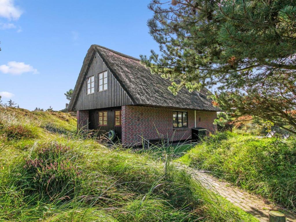 een klein bakstenen huis op een heuvel met een boom bij Holiday Home Grita - 500m from the sea in Western Jutland by Interhome in Vejers Strand