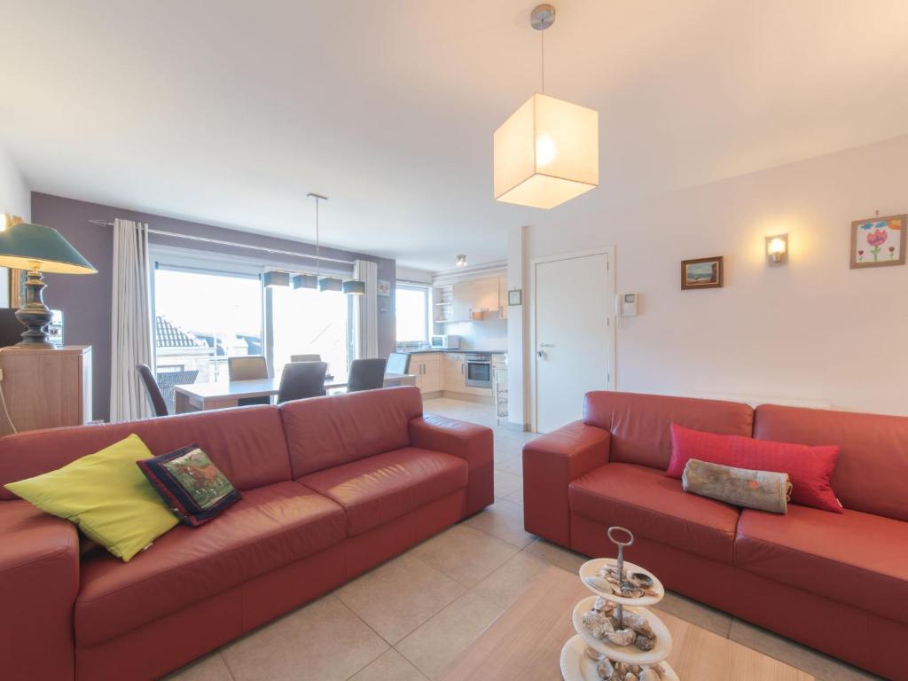 a living room with two red couches and a kitchen at Apartment Zeebries by Interhome in Bredene